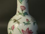 a white vase with pink flowers and a dragonfly on it