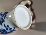 someone is holding a blue and white vase with a white lid