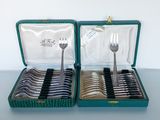two sets of forks and spoons in a green case
