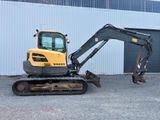 une petite pelleteuse garée devant un immeuble