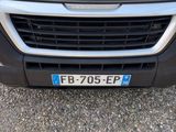 the front end of a white van with a blue license plate on it