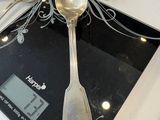 des cuillères et des cuillères à soupe posées sur une balance, sur un plan de travail de cuisine