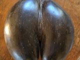 une aubergine noire posée sur une assiette en bois, sur une table