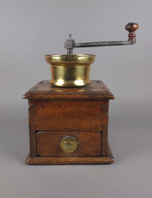 un moulin à café ancien avec un socle en bois et une plaque en laiton