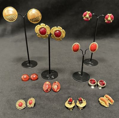 several pairs of gold and red earrings and brooches on stands