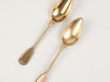 pair of gold colored spoons on a white surface