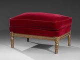 a red velvet foot stool with gold trim and wooden legs