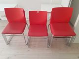 three red chairs sitting next to each other on a wooden floor