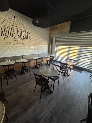 l'intérieur d'un restaurant avec des tables et des chaises, ainsi qu'une enseigne sur laquelle on peut lire « Darius Burger »