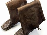 une paire de bottes en cuir marron posées sur une surface blanche, avec un fond blanc