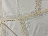 several pieces of white linen with lace on them on top of a bed