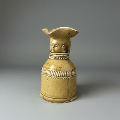 un vase jaune surmonté d'un oiseau