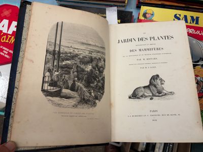 une personne tient un livre ouvert à la main devant une pile de livres