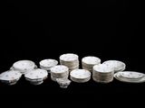 une pile d'assiettes blanches et argentées sur un fond noir