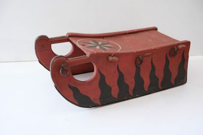un petit traîneau en bois orné d'un motif rouge et noir