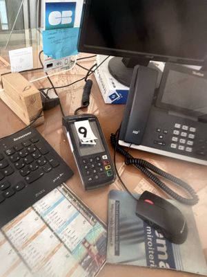 a desk with a computer, phone, and other electronics on it