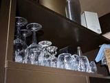 a shelf full of empty glasses and bottles in a kitchen