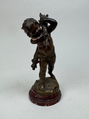 figurine en bronze représentant un garçon tenant une fleur dans ses mains