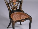 a black chair with a wicker seat and a basket on the back