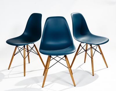 three blue plastic chairs with wooden legs against a white background