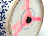 a blue and white vase with a pink design on it