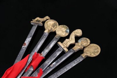 six swords with gold and red handles on a black background