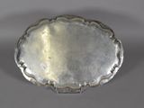 an antique silver plate with a scalloped edge on a gray surface