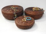 trois boîtes rondes en osier ornées de perles colorées, posées sur un fond blanc
