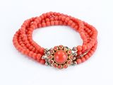 a close up of a bracelet with coral beads on a white background