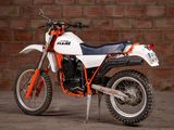a white and orange dirt bike parked in front of a brick wall