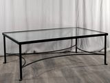 La table en verre est posée sur un parquet, devant un rideau blanc