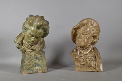 deux petits bustes en bronze représentant un homme et une femme, posés sur une table