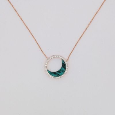 un collier vert et blanc avec un pendentif circulaire monté sur une chaîne en or