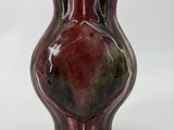 un petit vase posé sur une surface blanche