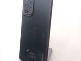 the back of a black cell phone sitting on top of a wooden stand