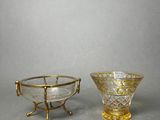 two glass bowls with gold rims and handles on a gray surface