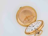 a gold pocket watch sitting on a white surface