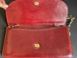 a person holding a red purse on top of a table