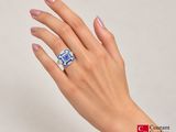 someone is holding a blue and white diamond ring in their hand