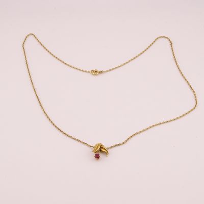 un collier en or avec une pierre rouge suspendue à une chaîne