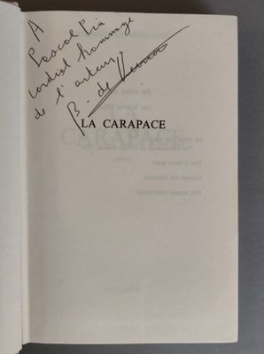 un livre ouvert, sur lequel figure une citation manuscrite, posé sur une table