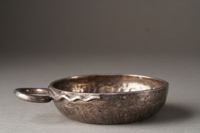 un bol en argent avec une cuillère sur une table