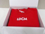 red t - shirt in a white box with the word dcm printed on it