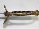 a gold and black sword on a white surface