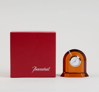 une horloge orange posée à côté d'une boîte rouge sur une surface blanche