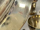a silver tea pot and a silver cup on a table