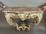 someone is holding a marble top table in front of a gray wall