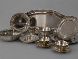 a group of silver plated dishes and bowls on a gray surface