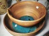 a bowl and a bowl on a table with vases in the background