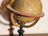 un petit globe en bois posé sur un socle, sur une table